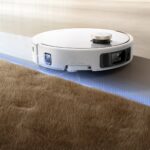 Illustration du fabricant : MOVA V50 Ultra Complete blanc longeant le bord d’un tapis.